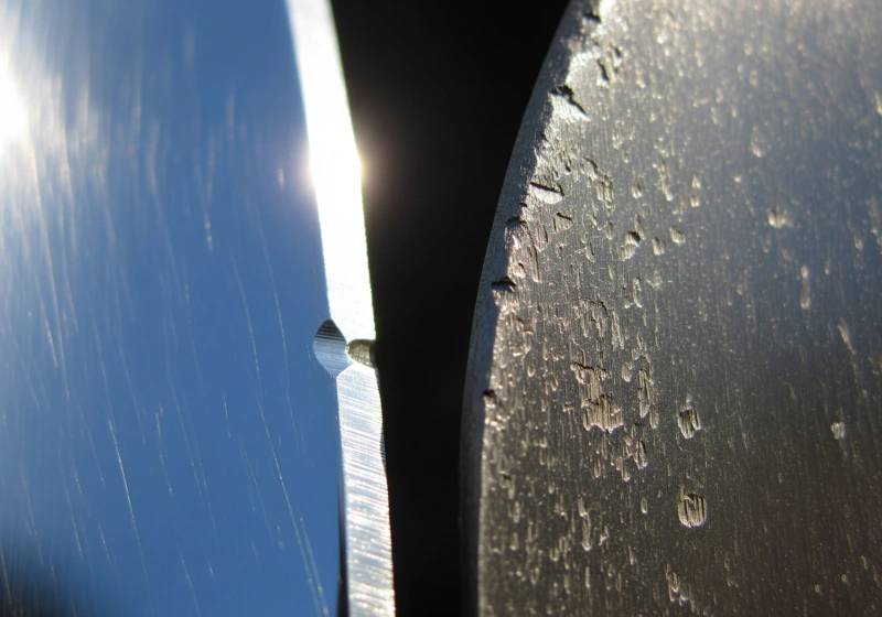Close-up comparison of a sharp, well-maintained lawn mower blade next to a dull, damaged blade showing the importance of proper maintenance