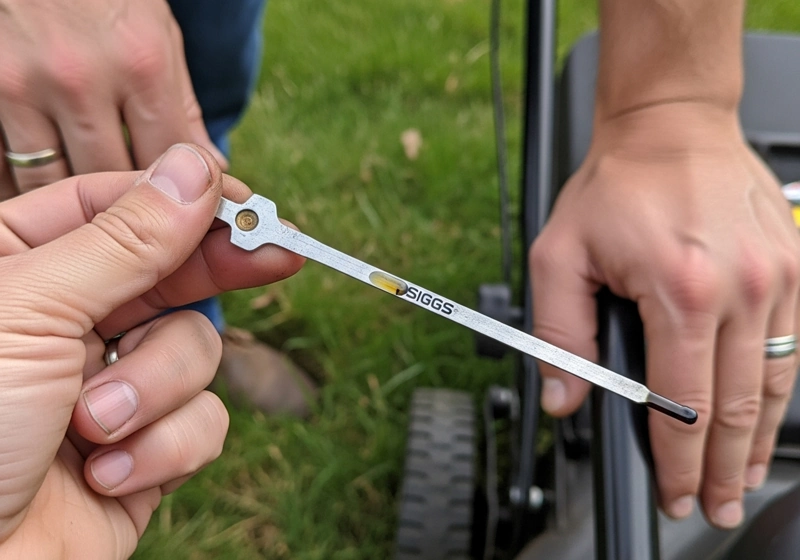 Homeowner checking oil dipstick on Briggs and Stratton lawn mower engine